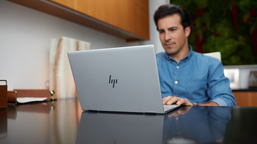 Man in blue shirt sitting in front of HP laptop in office