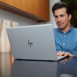 Man in blue shirt sitting in front of HP laptop in office