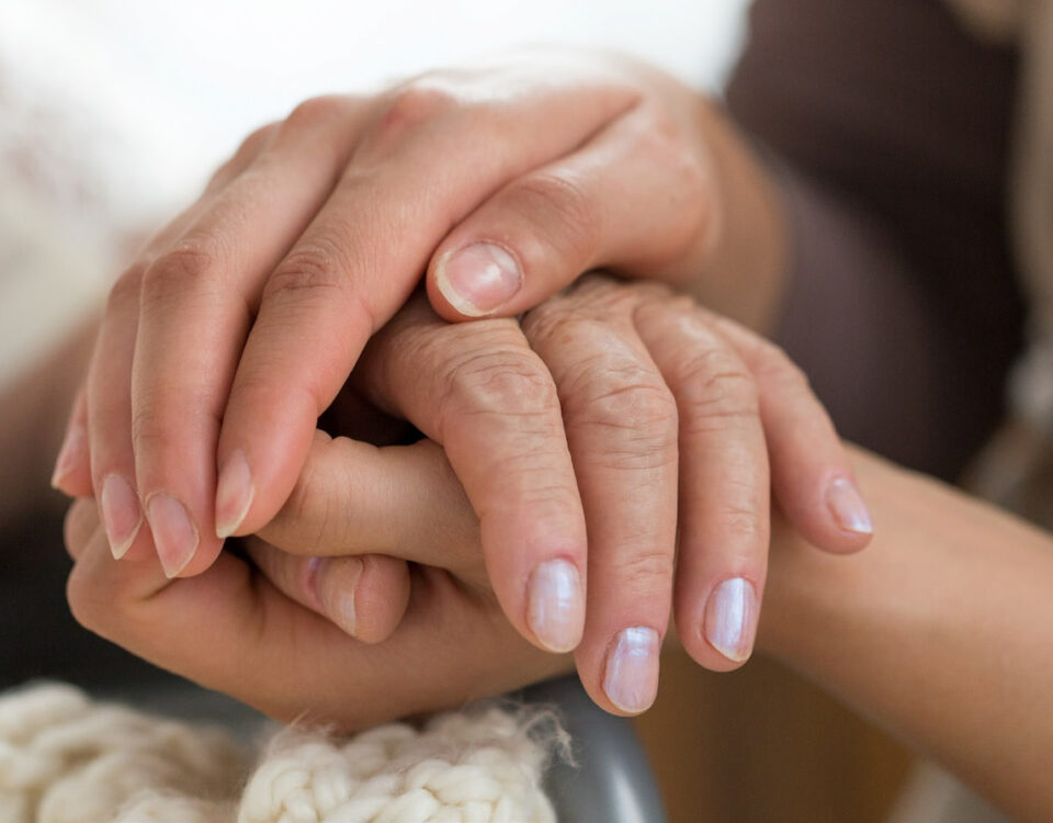 hospice woman holding elderly woman's hands