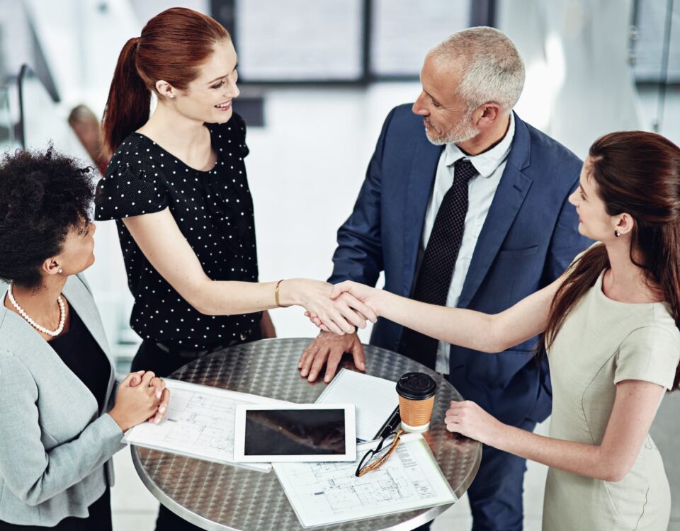 handshake-between four businesspeople around coffee table