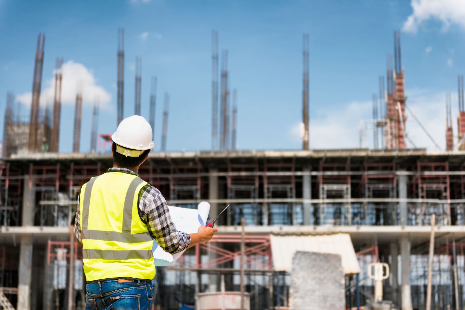 construction worker blueprints building scaffolds yellow vest