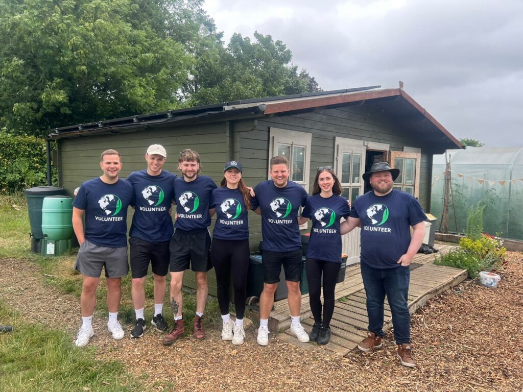Apogee marketing team volunteering at charity Communigrow, standing in front of newly painted HQ