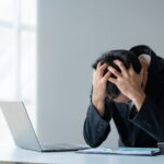 man at computer clutches his head in frustration