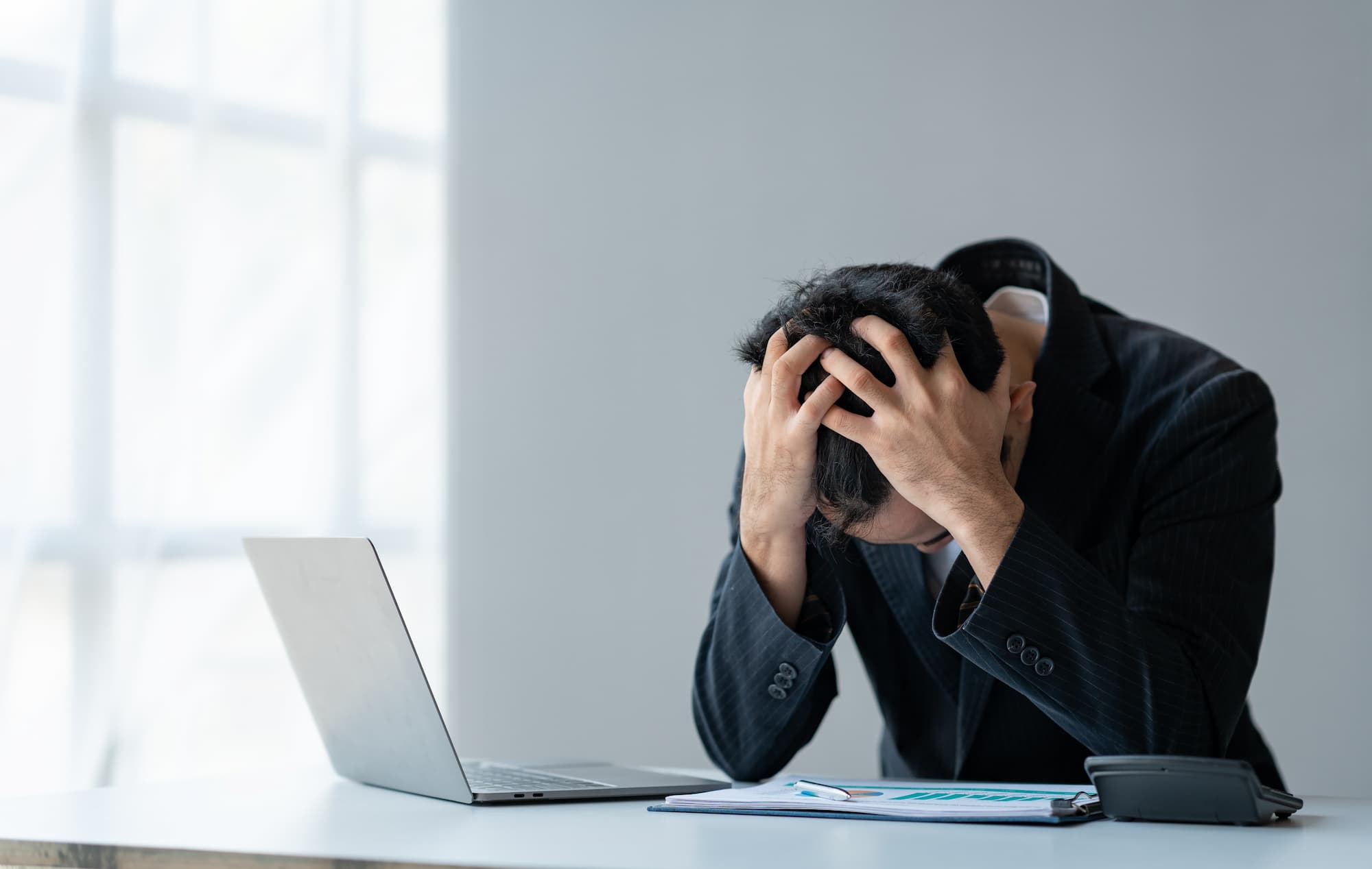man at computer clutches his head in frustration