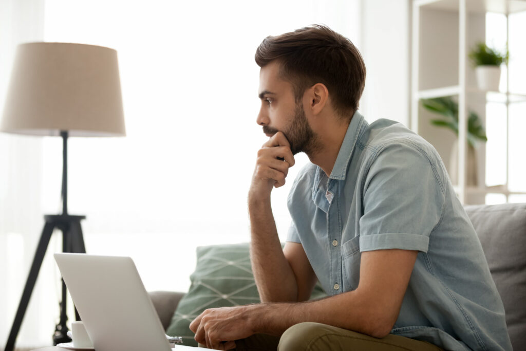 man looking contemplative in home office laptop
