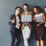 trendy young employees against grey background laptop