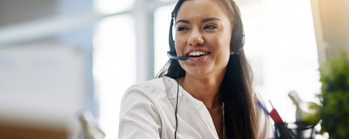 woman with telecom hands free headset smiling at desk