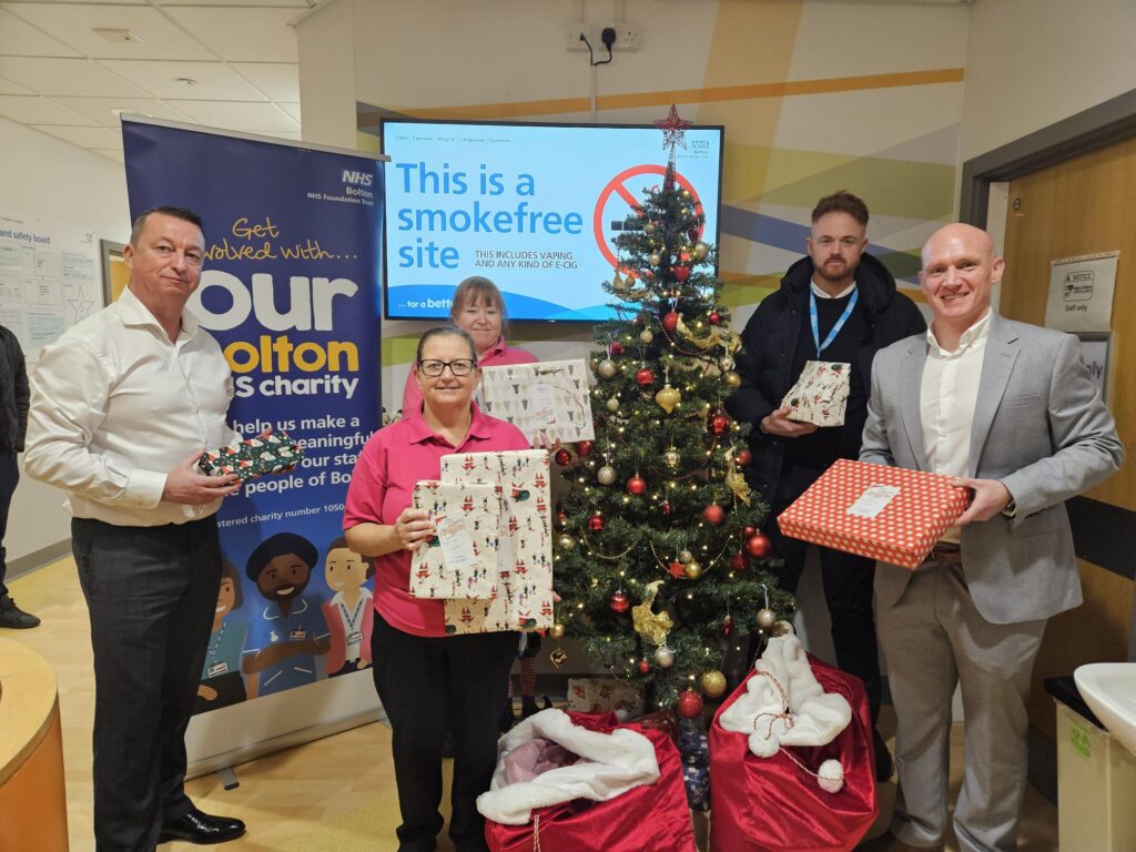 Die Teams von Apogee und Our Bolton Charity mit Weihnachtsgeschenken