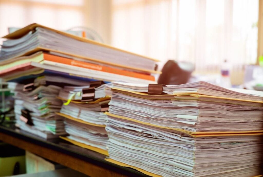 piles of binders containing paper documents in an office