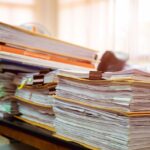 piles of binders containing paper documents in an office