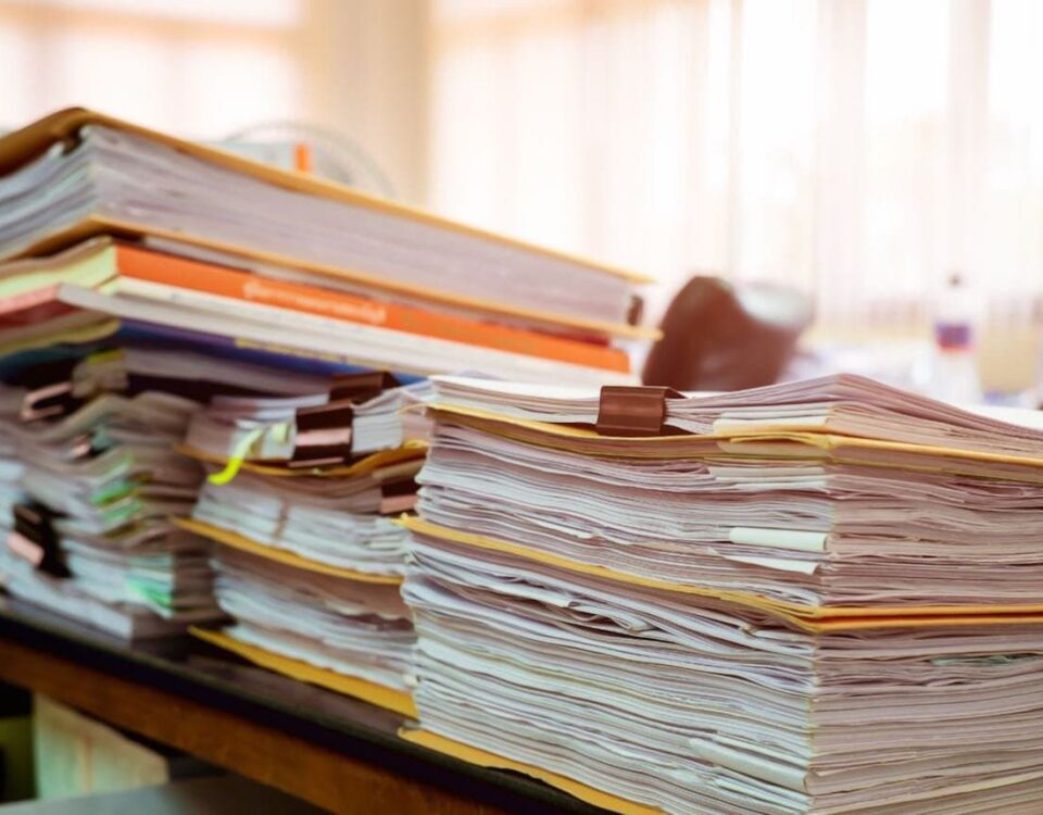 piles of binders containing paper documents in an office