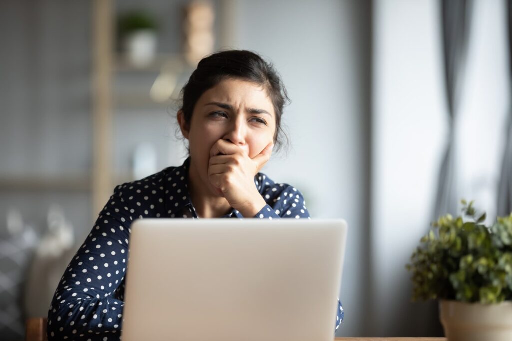 woman yawning at desk when hybrid working