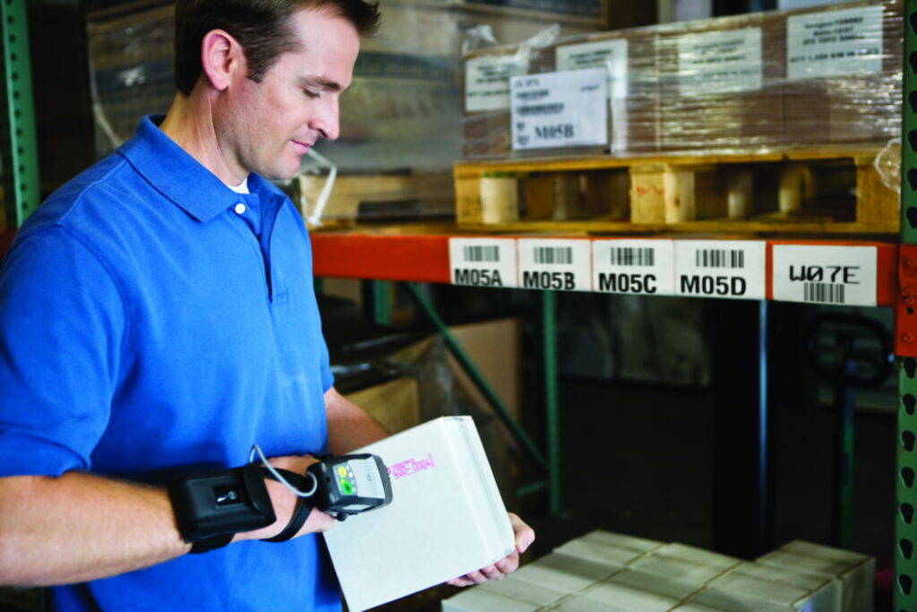 Man wearing blue shirt in warehouse scanning box barcode