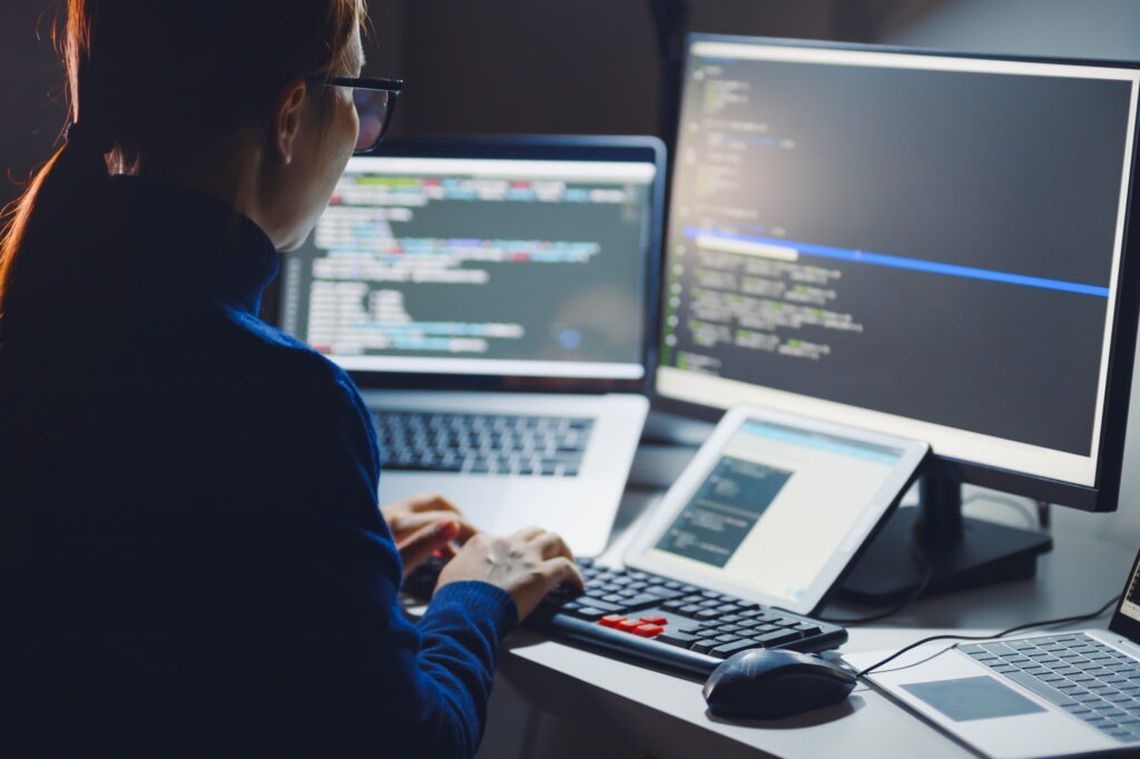 outsourced it services woman at computer with multiple monitors