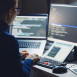 outsourced it services woman at computer with multiple monitors