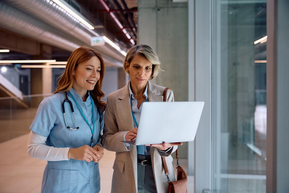 nhs staff two women nurse and business woman holding laptop